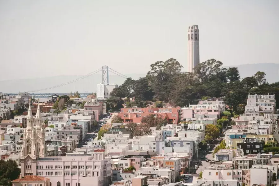 威尼斯人官网平台app科伊特塔(Coit塔)的背景是海湾大桥(Bay Bridge)和一座满是房屋的小山.