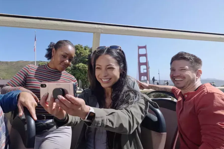 Un grupo de visitantes se toma una selfie en un recorrido en autobús cerca del puente Golden Gate. 加州威尼斯人官网平台app.